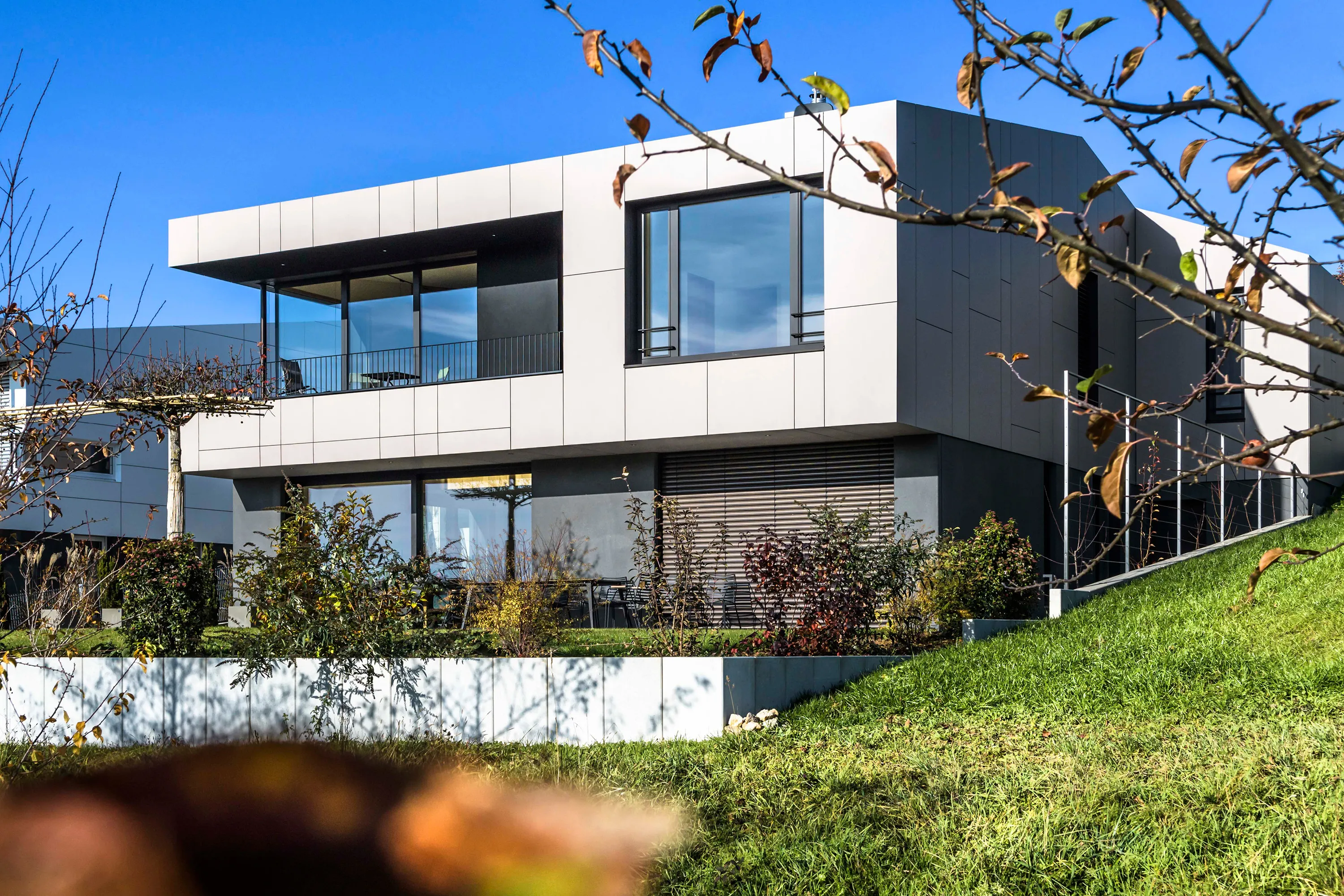 Außenansicht des Architektenhauses am Rebhügel mit großzügigen Glasfronten, Balkon und terrassiertem Garten
