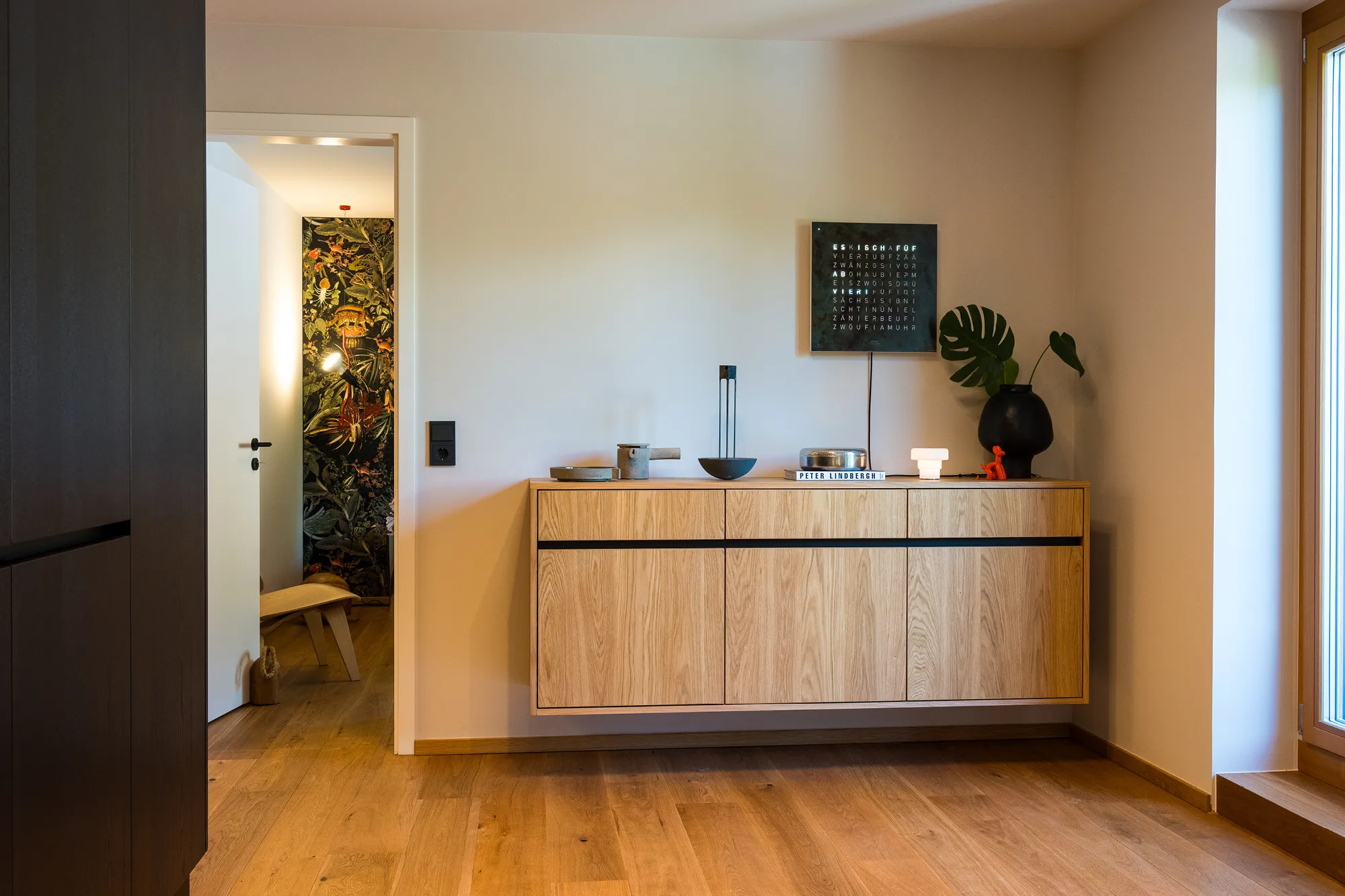 Schwebendes Eichen-Sideboard im Flur mit moderner Deko und Blick ins Schlafzimmer.