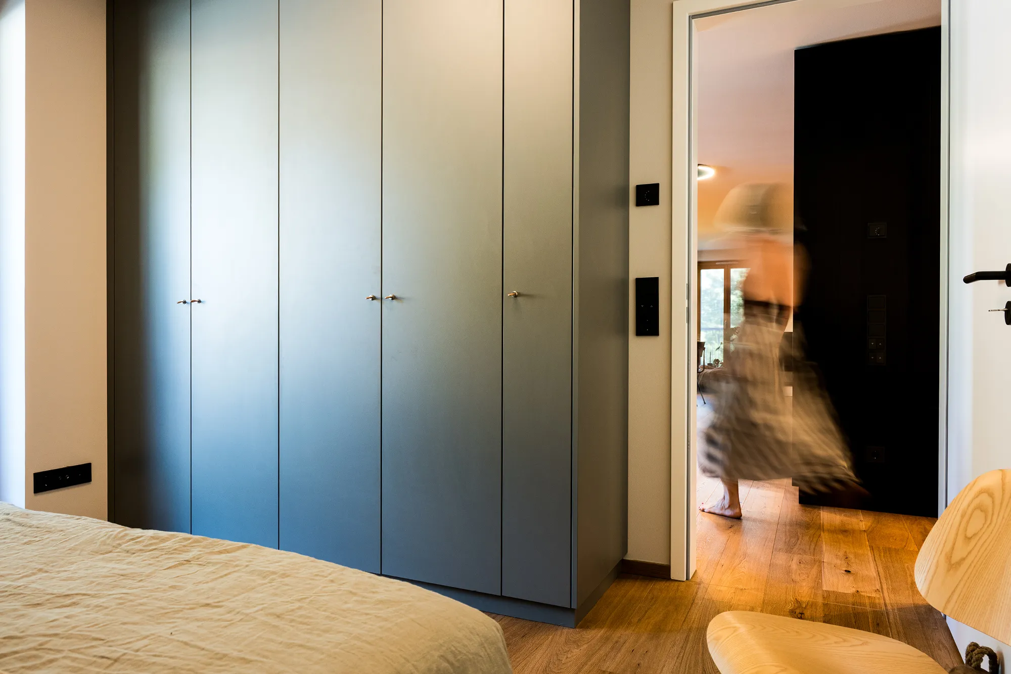 Graublauer, deckenhoher Einbauschrank im Schlafzimmer mit sanftem Blick in den Flur.