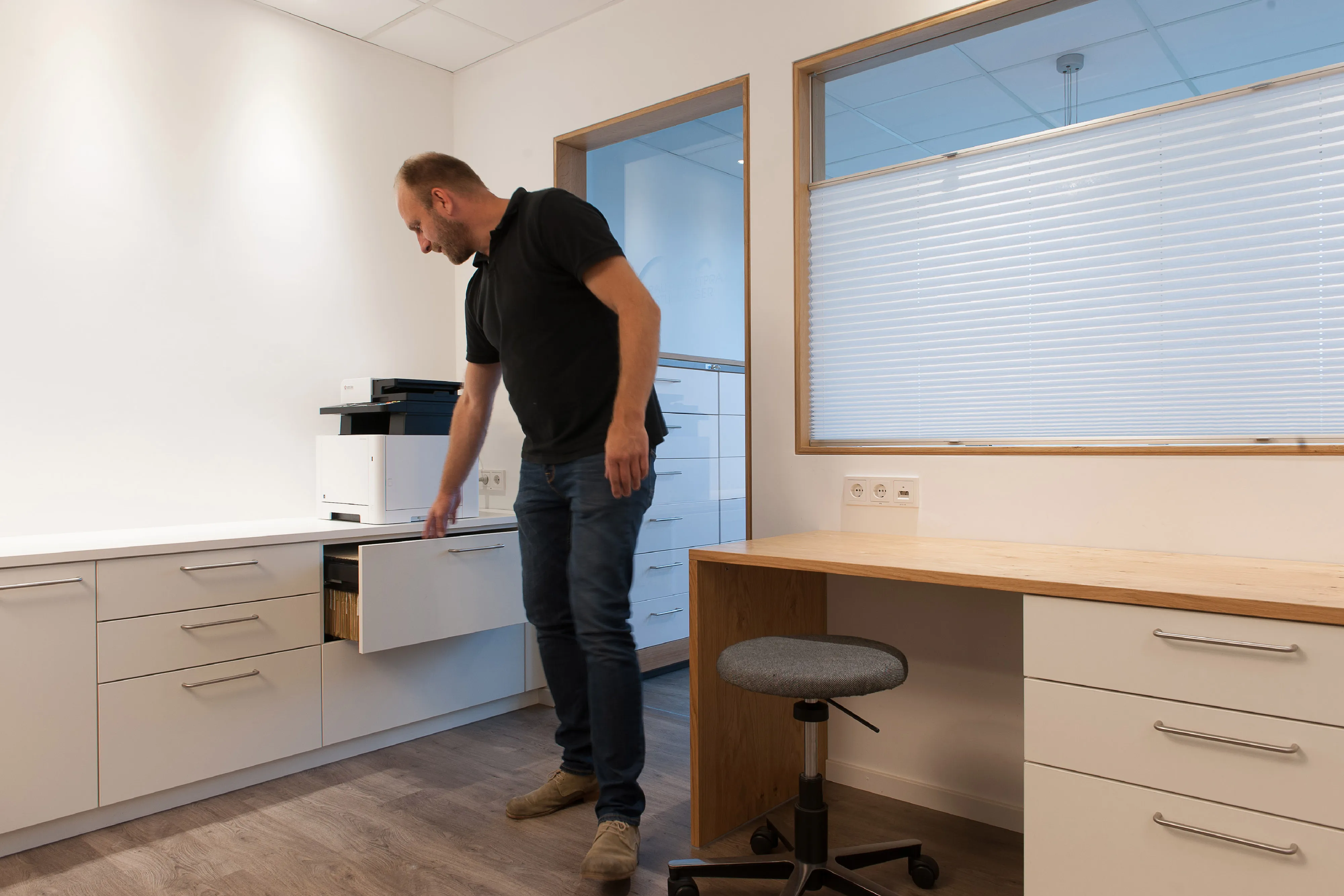Schreinermeister Bernhard Frankenhauser überprüft die Funktion des ausziehbaren Hängeregisters im maßgefertigten Büroschrank hinter der Empfangstheke.