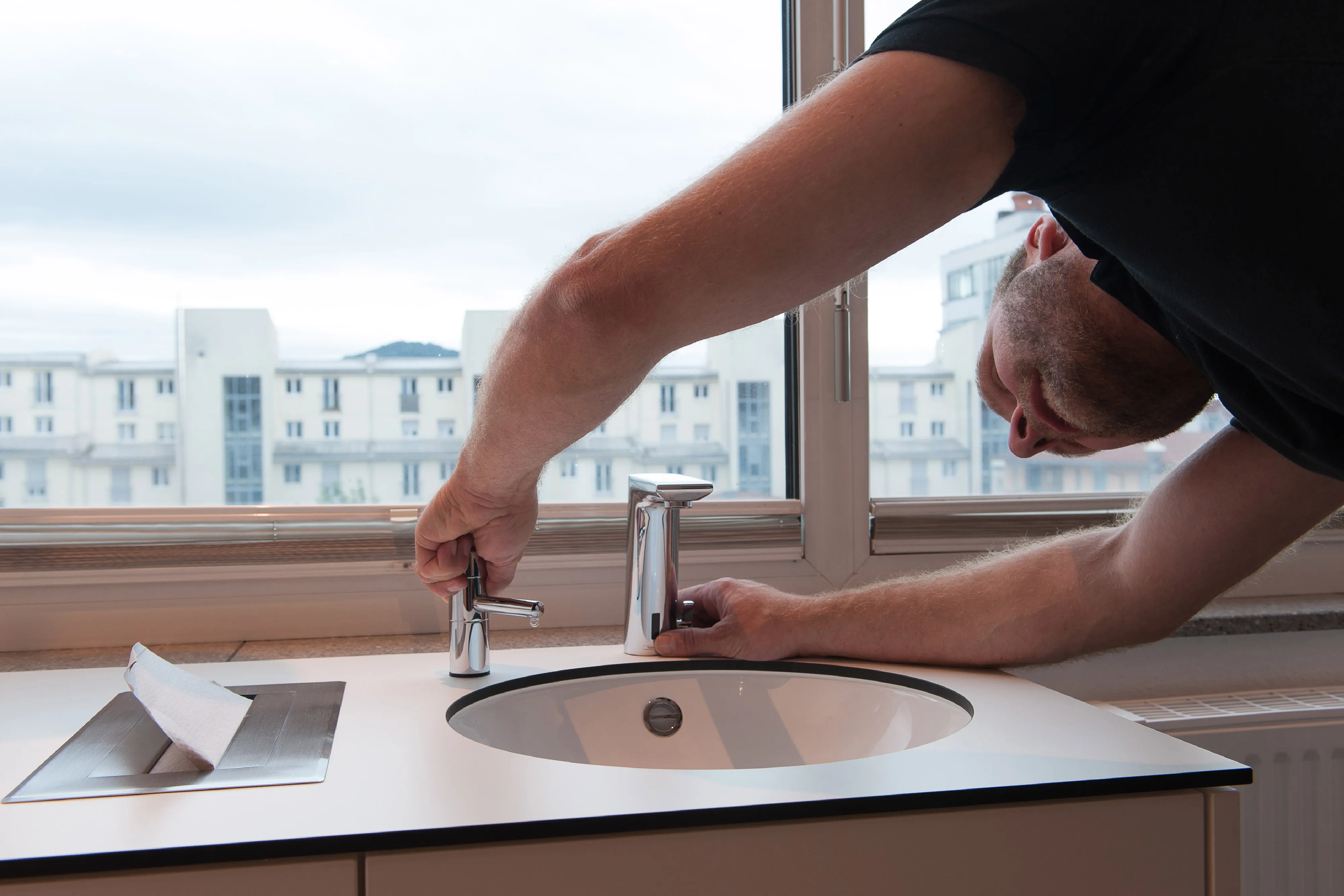 Bernhard Frankenhauser prüft die Funktionalität einer Armatur an einem nahtlos in die Arbeitsplatte integrierten Waschbecken.
