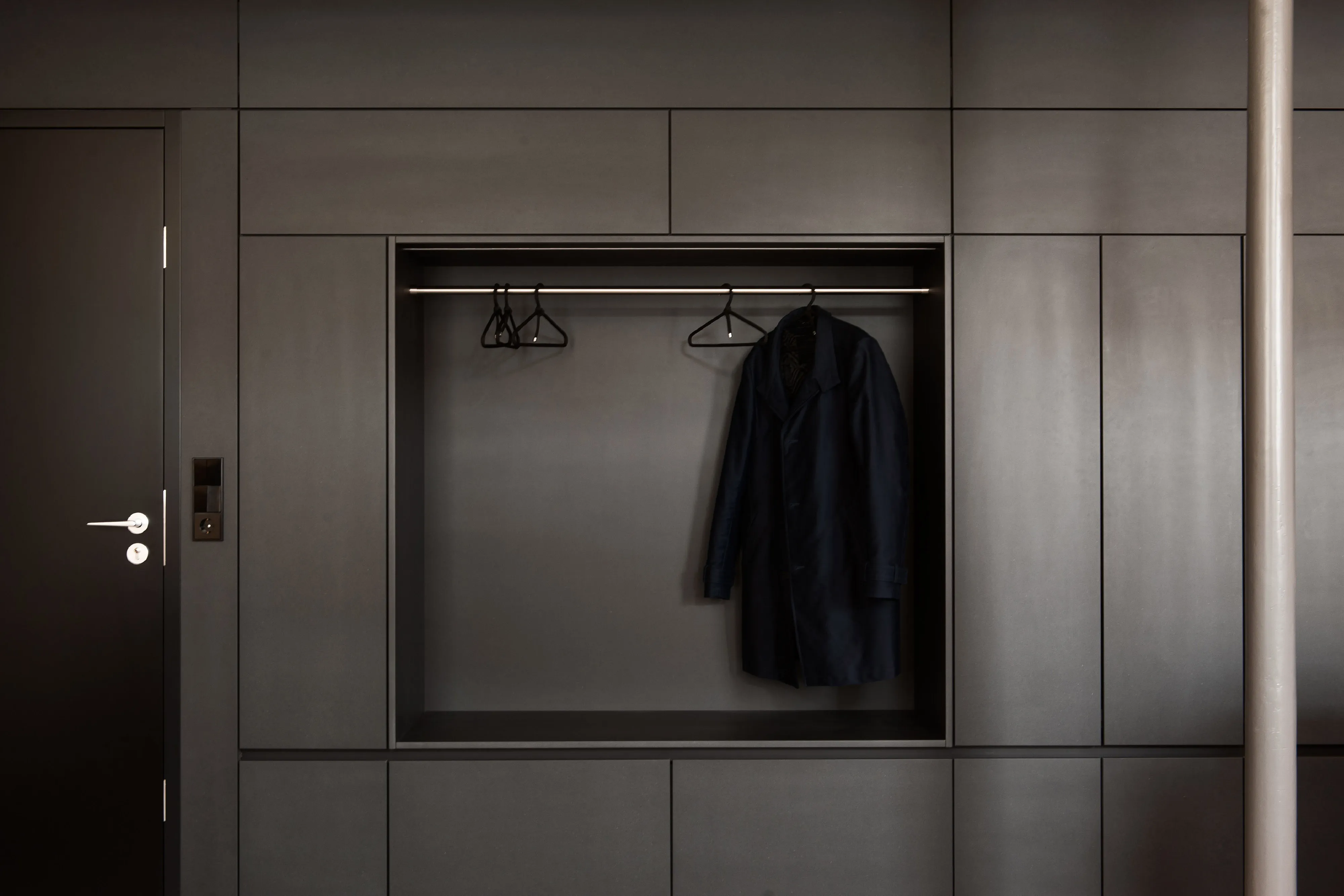 Frontalansicht der schwarzen Einbau-Garderobe mit integrierter Garderobennische, Kleiderstange und geschlossenem Stauraum.