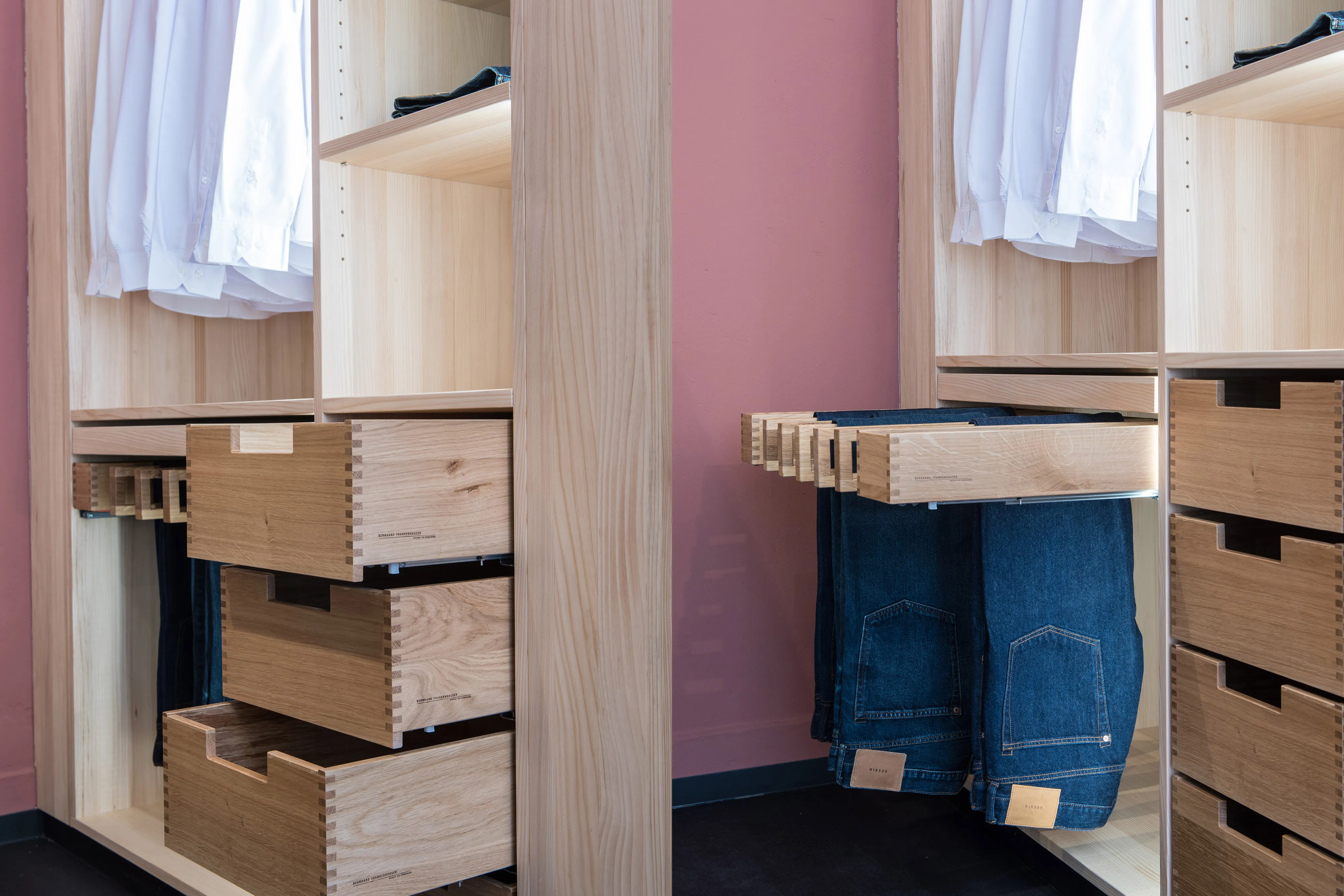 Detailansicht im Kleiderschrank: Geöffnete Holzauszüge mit gezinkten Ecken und ausziehbarer Hosenhalter aus Massivholz.