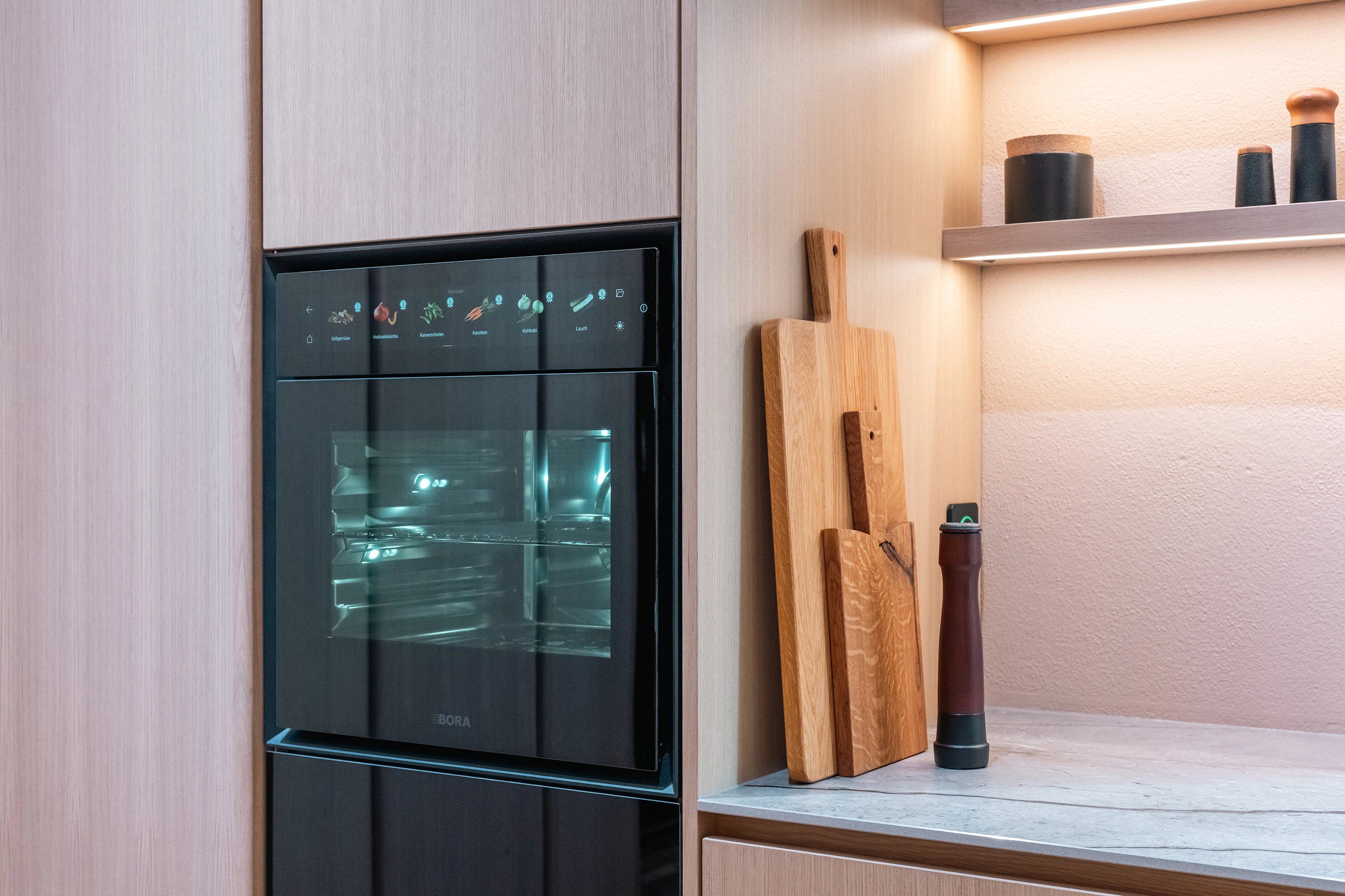 Nahaufnahme des schwarzen BORA X BO Dampfbackofens mit Touch-Display in einer hellen Holzfront.