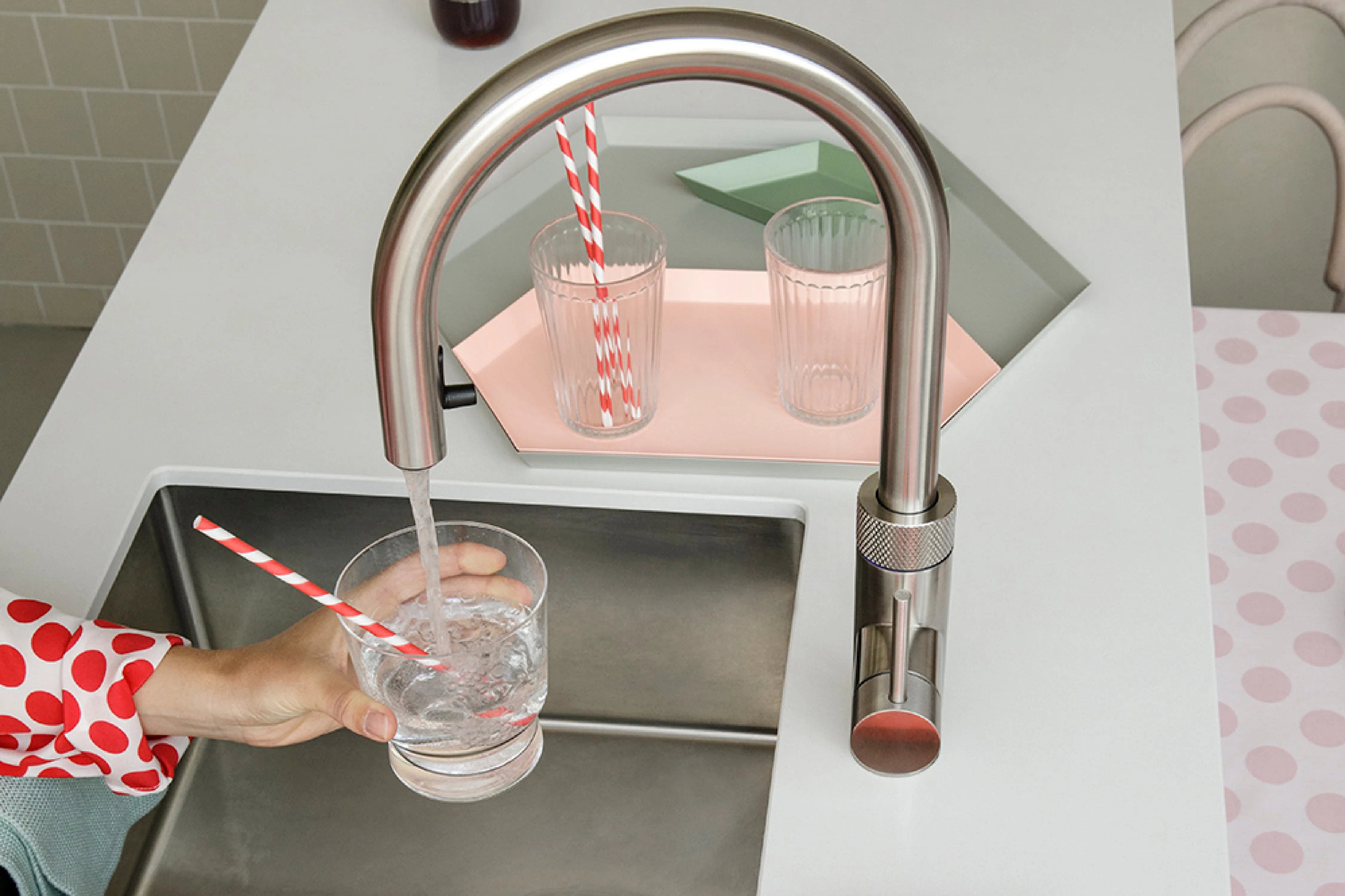 Nahaufnahme: Frisch gekühltes sprudelndes Wasser wird aus einem Quooker-Armatur-Bogen in ein Trinkglas gefüllt
